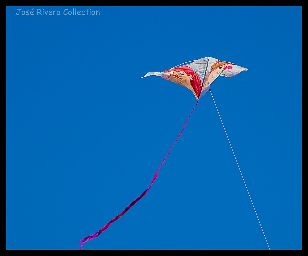 A kite with a long red tail against a blue sky